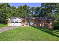 Charming brick home with a well-manicured lawn and attached garage in a treed area at 3341 Rae Pl, Lawrenceville, GA 30044