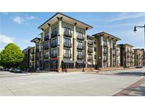 Contemporary apartment building featuring tan brick, black balconies, and commercial space on the ground floor at 5300 Peachtree Rd # 2309, Chamblee, GA 30341