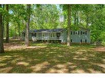 Charming single-story home with a cozy front porch, surrounded by mature trees and lush landscaping at 411 Buckingham Cir, Marietta, GA 30066