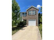 Two-story brick home featuring a two-car garage and well-maintained lawn with mature trees at 2056 Belmont Cir, Conyers, GA 30012