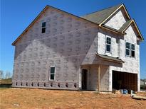 New construction home showing exterior framing details and wrapped for weather protection on a sunny day at 1227 Riverstone Rd, Jonesboro, GA 30238
