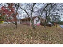Charming single-story home featuring a covered front porch, mature trees, and an expansive front yard at 4128 Worth Nw St, Acworth, GA 30101