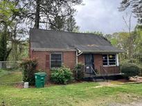 Quaint brick home with a compact front yard and black framed windows, surrounded by mature trees at 3095 Rainbow Dr, Decatur, GA 30034