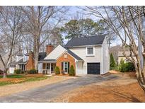 Charming home with a brick accent, well-manicured landscaping, and a long driveway leading to a one-car garage at 302 Roswell Green Ln, Roswell, GA 30075