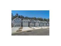 A row of attractive townhouses with a modern, gray exterior, garage doors, and well-kept landscaping, all under a clear blue sky at 5154 Longview Run, Decatur, GA 30035