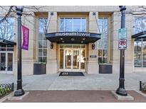 Museum Tower building entrance with brick facade, glass doors, and sidewalk planters at 285 Centennial Olympic Park Dr # 1705, Atlanta, GA 30313