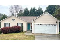 Charming one story home with a lush green lawn and a bright teal front door and a two car garage at 413 Remington Ct, Villa Rica, GA 30180