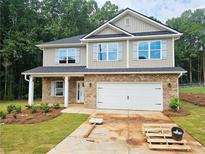Two-story home featuring a brick and vinyl facade, a two-car garage, and well landscaped front yard at 305 Melanie Ct, Bowdon, GA 30108