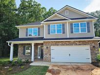 Charming two-story home featuring a brick facade and neutral-colored siding, complemented by gray shutters and a two-car garage at 305 Melanie Ct, Bowdon, GA 30108