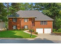 Charming brick home with a well-manicured lawn and a two-car garage nestled among lush trees at 4956 Braeburn Nw Trce, Acworth, GA 30102