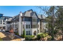 Beautiful multi-story home featuring a brick facade, dark roof and trim, and professionally landscaped grounds at 6616 Aria Village Dr, Atlanta, GA 30328