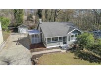 Charming home with a screened-in porch, lush lawn, gray siding, and a detached garage at 19 Grove Park Nw Pl, Atlanta, GA 30318