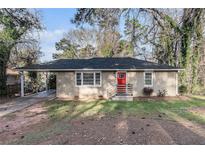 Charming single-story brick home with a red front door and covered carport, nestled among mature trees at 2203 Knoll Dr, Decatur, GA 30032