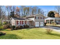 Charming two-story home with a brick facade, red shutters, a well-manicured lawn, and an attached two-car garage at 6784 Tilton Ln, Peachtree Corners, GA 30360