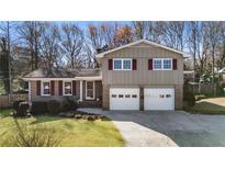 Charming home featuring a well-manicured lawn, two car garage, and a mix of siding and brick at 6784 Tilton Ln, Peachtree Corners, GA 30360
