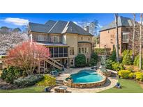 Resort-style backyard featuring a custom pool, stone patio, and lush landscaping, perfect for outdoor entertaining at 2260 Wood Falls Dr, Cumming, GA 30041