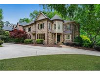 Stately stone home with manicured lawn, mature trees, and circular driveway at 2260 Wood Falls Dr, Cumming, GA 30041