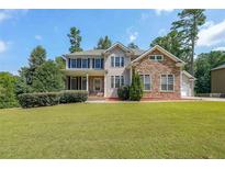 Inviting two-story home featuring a well-manicured lawn, stone accents, and a classic facade at 4408 Meadowwood Dr, Loganville, GA 30052