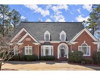 Beautiful two-story brick home featuring dormer windows and manicured landscaping at 2758 Chieftain Run, Duluth, GA 30097