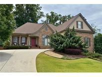 Charming stone home with a well-manicured lawn, mature trees, and a welcoming front porch with rocking chairs at 1976 Hedge Brooke Nw Trl, Acworth, GA 30101