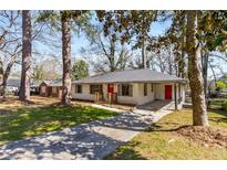 Charming single-story home with a bright red door, brick accents, and mature trees in a well-manicured lawn at 2462 Macon Sw Dr, Atlanta, GA 30315