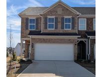 Two-story brick townhome with a two car garage, gray shutters, and well manicured landscaping at 839 Pensive Run, Dacula, GA 30019