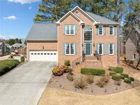 Charming two-story brick home boasts mature landscaping, attached garage, and inviting front entrance at 2135 Primrose Place Ln, Lawrenceville, GA 30044