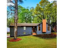 Charming single-Gathering home with gray siding, stone accents, modern chimney, and inviting front yard at 2512 Hidden Hills Dr, Marietta, GA 30066