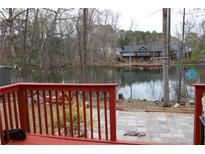 A view from the red deck overlooking a calm lake and a patio area in the backyard at 3179 Dunlin Lake Rd, Lawrenceville, GA 30044