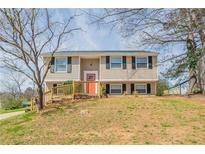 Charming two-story home with tan siding, black shutters, a red front door, and a wooden porch and rails at 5415 Tracey Dr, Stone Mountain, GA 30088
