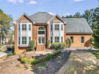Charming two-story brick home featuring a well-manicured lawn and complemented by mature trees at 12105 Wexford Club Dr, Roswell, GA 30075