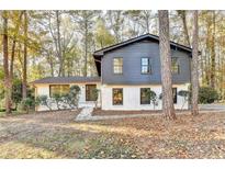 Inviting two-story home with a painted brick base and dark wood paneled second story among mature shade trees at 2887 Hickory Ln, Snellville, GA 30078