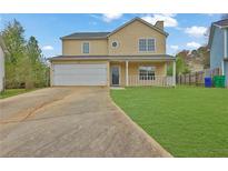 Inviting two-story home with a well-manicured lawn, front porch, and attached two-car garage at 864 Oakhill Ct, Stone Mountain, GA 30088