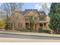 Inviting brick home featuring a covered porch, manicured landscaping, and charming architectural details at 2315 Monet Dr, Cumming, GA 30041