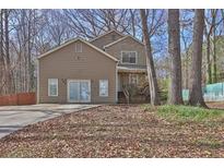 Two-story home featuring a front yard with mature trees and a well-maintained lawn on a sunny day at 585 Lake Dr, Snellville, GA 30039