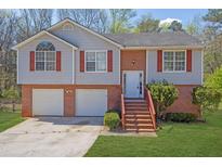Charming home featuring a two-car garage, brick accents, and a welcoming front entrance with stairs at 3021 Hampton Club Way, Lithonia, GA 30038