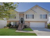 Charming two-story home featuring a brick and vinyl facade, attached garage, and well-maintained front yard at 2551 Tolliver Dr, Ellenwood, GA 30294