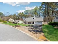 Charming single-story home featuring a two-car garage and well-manicured front lawn at 10245 Old Woodland Entry, Alpharetta, GA 30022