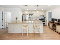 Bright kitchen featuring an island with a granite countertop, stainless steel appliances, and modern pendant lighting at 2466 Thrasher Rd, Buford, GA 30519