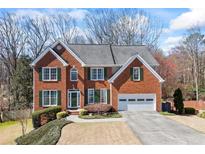 Charming two-story brick home featuring a two-car garage, well-manicured lawn, and traditional architectural details at 1168 Blackhawk Pl, Lawrenceville, GA 30043