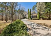 Charming traditional home with a long driveway lined with lush greenery and mature trees at 1345 Bridgemill Ave, Canton, GA 30114