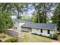 Charming home with neutral siding, dark roof, and a partially fenced front yard, surrounded by mature trees at 6405 Cherry Tree Ln, Atlanta, GA 30328