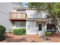Two-story townhouse with a small front yard, a wooden balcony, and white siding, creating a cozy and inviting home at 6 Nw Fairway Nw Dr, Kennesaw, GA 30144