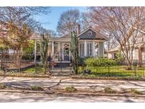 Charming bungalow-style home with inviting front porch and mature trees, framed by a decorative wrought iron fence at 1069 Colquitt Ne Ave, Atlanta, GA 30307