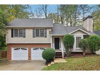 Charming two-story home with a brick foundation, black shutters, and an attached two-car garage at 3450 Lookout Trce, Powder Springs, GA 30127