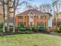 Traditional brick home with manicured front lawn, mature trees, and inviting entryway at 3672 Howell Wood Nw Trl, Duluth, GA 30096