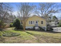 Charming yellow home featuring a well-manicured front lawn and inviting curb appeal at 1989 Mount Vernon Rd, Atlanta, GA 30338
