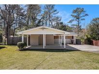 Exterior home view with carport, front lawn, and mature trees under blue sky at 2131 Columbia Dr, Decatur, GA 30032