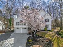 Charming two-story home with a well-manicured lawn and a beautiful flowering tree in the front yard at 210 Barrett Springs Way, Canton, GA 30115