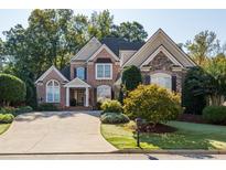 Beautiful two-story brick and stone home with lush landscaping and a long driveway leading to a spacious garage at 7085 Wakehurst Pl, Cumming, GA 30040